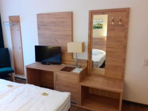 1 dormitorio con espejo, TV y cama en Land-gut-Hotel Zum alten Forsthaus - Aufladestation für Elektroautos, en Hürtgenwald