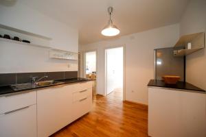 cocina con armarios blancos y suelo de madera en Apartments Harbour, en Senj