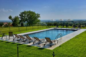 a pool with chairs and tables and a fence at Agriturismo La Guarda in Picedo