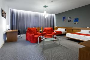 a hotel room with two beds and red chairs and a table at Moscow House Hotel in Yerevan +34 photos