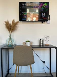 a desk with a chair and a television on a wall at NG SuiteHome - Lille I Roubaix I Gare I Métro Alsace - Netflix - Wifi in Roubaix