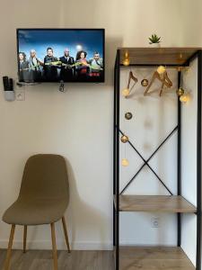 a flat screen tv on a wall next to a chair at NG SuiteHome - Lille I Roubaix I Gare I Métro Alsace - Netflix - Wifi in Roubaix