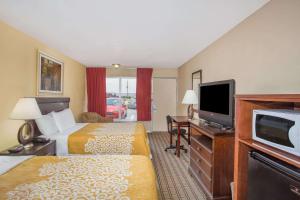 a hotel room with two beds and a flat screen tv at Days Inn by Wyndham Blytheville in Blytheville