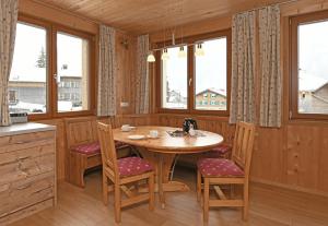 cocina con mesa de madera, sillas y ventanas en Schmiedlarhof, en Au im Bregenzerwald