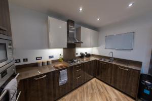 eine große Küche mit Holzschränken und einem Waschbecken in der Unterkunft Oakhill Apartment in Aberdeen