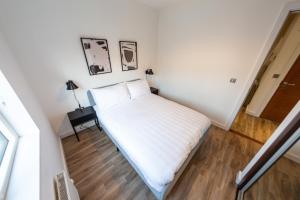 a small white bedroom with a bed and a table at Oakhill Apartment in Aberdeen