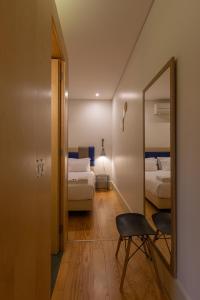 Habitación con 2 camas, espejo y silla. en ORM - Almada Balcony Apartment, en Oporto 14 fotos más