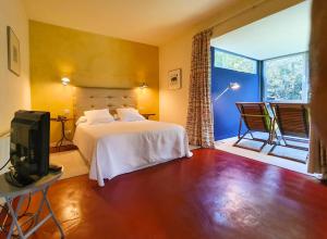 Un dormitorio con una cama y un televisor y una ventana. en La Posada, en Llanes