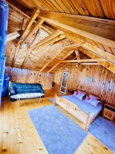 - une chambre avec un lit et un canapé dans une cabane en rondins dans l'établissement Cabana Vânătorilor, à Poiana Mărului