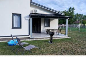 a house with a deck with chairs and a grill at Comfort Ház in Balatonőszöd