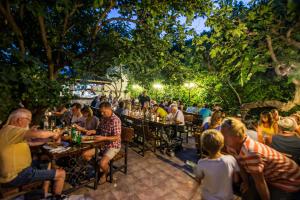 eine Gruppe von Personen, die an Tischen in einem Restaurant im Freien sitzen in der Unterkunft Apartments Yelkouan in Biograd na Moru