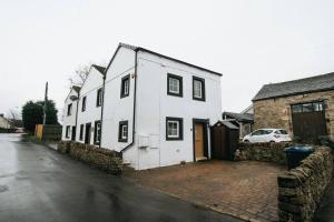 a white house on the side of a street at WILSONS COTTAGE - 2 Bed Classic Cottage located in Cumbria with a cosy fire in Camerton