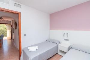a white bedroom with two beds and a hallway at Aparto Residence Galetamar in Calpe