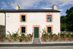 ein weißes Haus mit grüner Tür und Blumen in der Unterkunft Castletown Gate House in Celbridge
