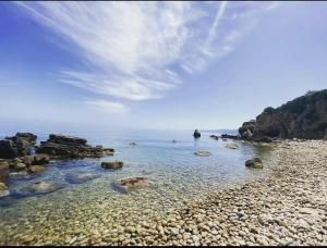 a rocky beach with the water and rocks at Rais Gerbi Appartamento in Pollina