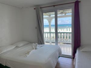 um quarto com uma cama e vista para o oceano em The Wave Hostel Corn Island em Ilhas do Milho