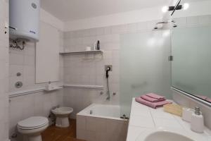 ein weißes Badezimmer mit einem WC, einer Badewanne und einem Waschbecken in der Unterkunft A Balcony on Lake Maggiore in Belgirate