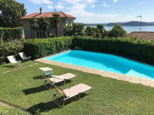 een zwembad met twee stoelen en een tafel in het gras bij A Balcony on Lake Maggiore in Belgirate