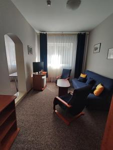 a living room with a blue couch and a tv at Hotel Sudety in Głuchołazy