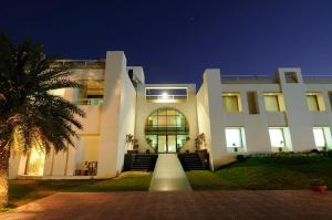 a large white building at night with a palm tree at Inder Residency Resort & Spa Udaipur in Udaipur