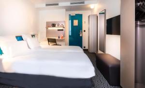 a bedroom with a large white bed and a desk at Libertel Canal Saint Martin in Paris