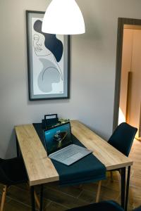 a laptop computer sitting on a wooden table with a lamp at Manoir Apartments City Center in Novi Sad