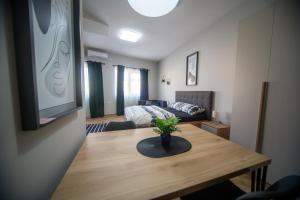 - un salon avec une table et un lit dans l'établissement Manoir Apartments City Center, à Novi Sad