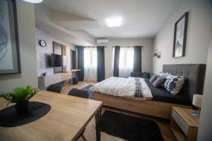 a bedroom with a bed and a table in a room at Manoir Apartments City Center in Novi Sad