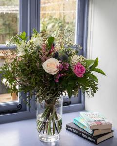 un jarrón de flores en una mesa con libros en The Nog Inn en Wincanton