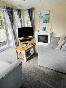 un salon avec un canapé, une télévision et une table dans l'établissement Fairview Lodge with Hot Tub, à Barmby on the Moor