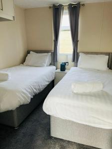 deux lits dans une petite pièce avec une fenêtre dans l'établissement Fairview Lodge with Hot Tub, à Barmby on the Moor