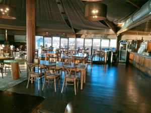 un ristorante con tavoli e sedie in legno e finestre di BJ Chalets - De Rug 1 - Vakantiepark Lauwersoog - LUXE chalet met vaatwasser! Vroege incheck! a Lauwersoog