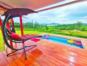 Ban Khao Dok Mai的住宿－บ้านฟาร์มรักพูลวิลล่าวิวทะเลสาปแก่งกระจาน，一个带椅子和遮阳伞的甲板和一个游泳池
