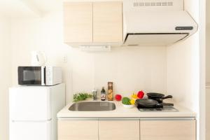 Una cocina con fregadero y refrigerador blanco. en Nedoco Osaka West, en Osaka