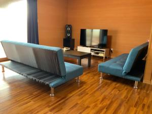 a living room with two blue chairs and a television at AZ Hotel in Amami - Villa with private outdoor Jacuzzi in Amami