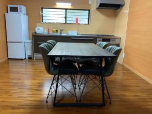 a table and chairs in a kitchen with a refrigerator at AZ Hotel in Amami - Villa with private outdoor Jacuzzi in Amami