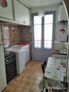 een keuken met een wastafel, een tafel en een deur bij Appartement 1er étage banyuls sur mer départs et arrivées les samedis in Banyuls-sur-Mer