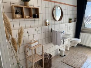 a white tiled bathroom with a toilet and a mirror at Schlafen über der Whiskybar in Rüdesheim am Rhein +34 photos