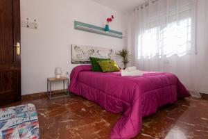 a bedroom with a pink bed with a purple blanket at Casa de la Vega in Cúllar-Vega +36 photos
