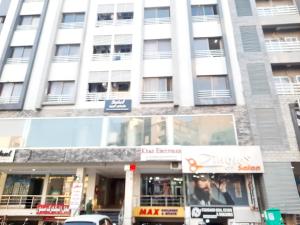 a tall white building with windows on a street at The Red one bedroom apartment in Bahria Town in Rawalpindi