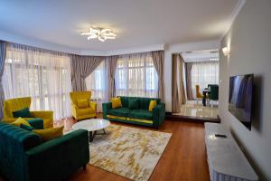 a living room with green couches and yellow chairs at Takimu Villas Thika in Thika