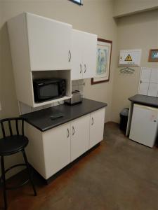 a kitchen with white cabinets and a microwave at Fountain Baths Guest Cottages in Barberton