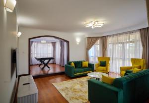 a living room with two green couches and a piano at Takimu Villas Thika in Thika