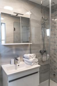 y baño con lavabo y ducha con toallas. en Comfort Apartment Dorin, en Makarska