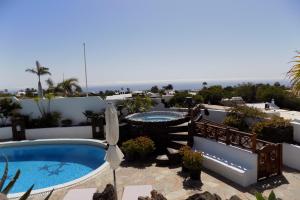 um pátio com uma piscina e um guarda-sol em Finca Paraíso - Finest Villa with incredible views over Puerto del Carmen em Puerto del Carmen
