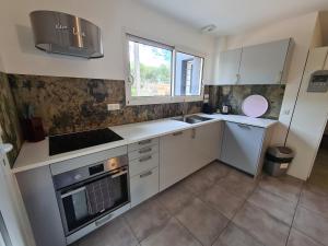 a kitchen with white cabinets and a sink and a window at Etoiles de Provence DUO ROMANTIC in La Ciotat