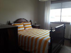 Arcozelo的住宿－Oporto Beach House，一间卧室配有一张带条纹床单的床和窗户。