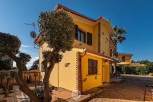 une maison jaune avec un arbre devant dans l'établissement Villa Monica - Suites, à Iglesias 39 autres photos