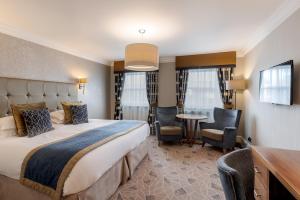 Skiddaw Hotel في كيسويك: غرفة فندقية بسرير وطاولة وكراسي