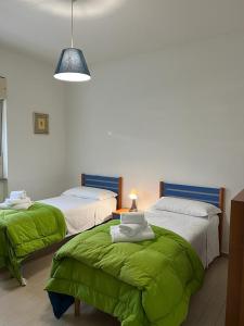 two beds with green sheets in a room at La Torretta in LʼAquila